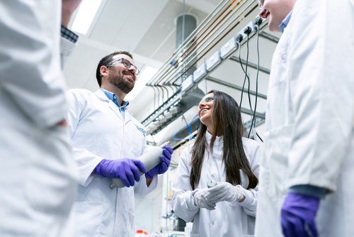 Photo of scientists in a lab smiling at each other