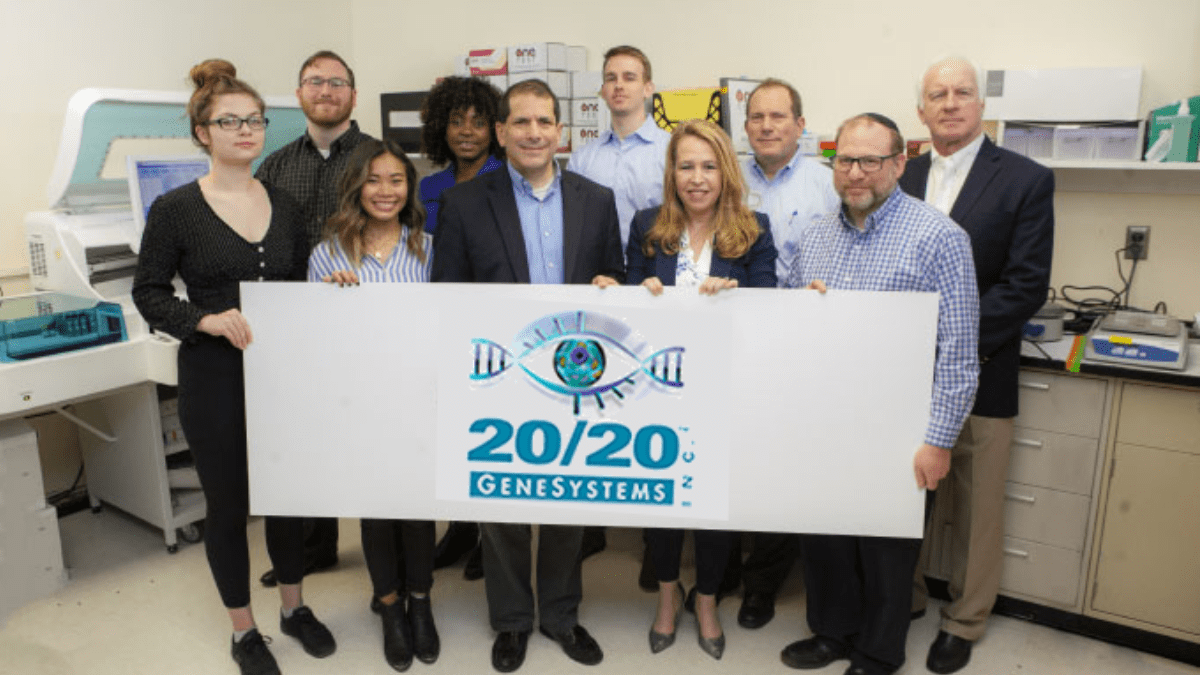 20/20 Gene Systems leadership holding a company banner